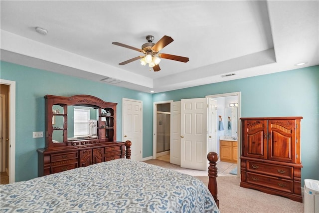 carpeted bedroom with connected bathroom, a raised ceiling, and ceiling fan