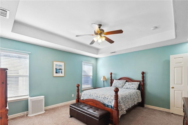 carpeted bedroom featuring a tray ceiling and ceiling fan