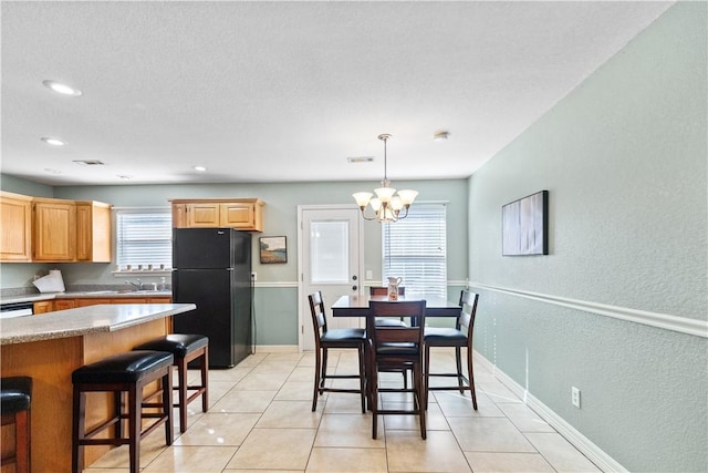 dining space with light tile patterned floors, a notable chandelier, and sink