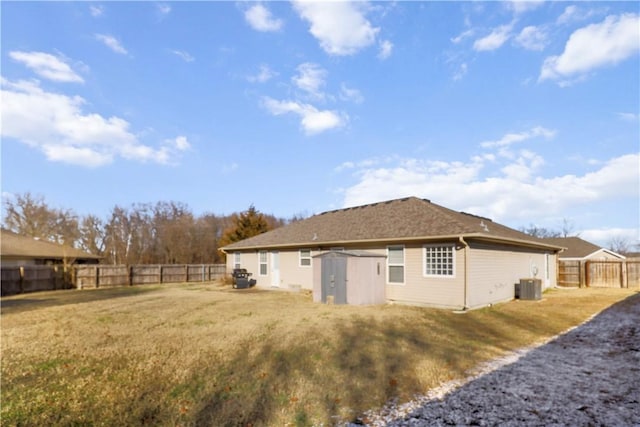 rear view of house with central AC unit, a storage shed, and a yard