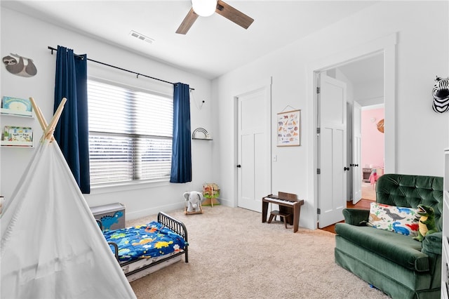 carpeted bedroom with visible vents, a ceiling fan, and baseboards