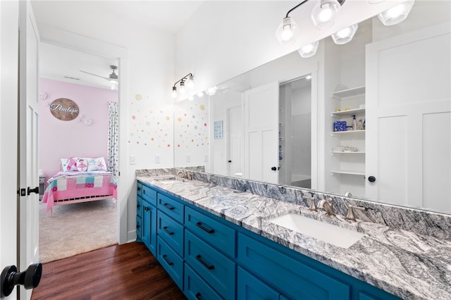 bathroom featuring double vanity, wood finished floors, a ceiling fan, and a sink