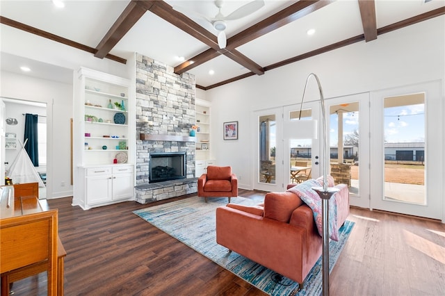 living room with hardwood / wood-style flooring, a stone fireplace, built in shelves, and beam ceiling