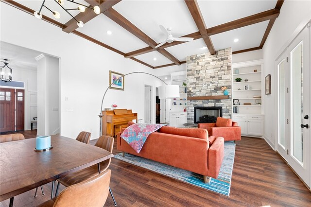 living area featuring beamed ceiling, coffered ceiling, a stone fireplace, and wood finished floors