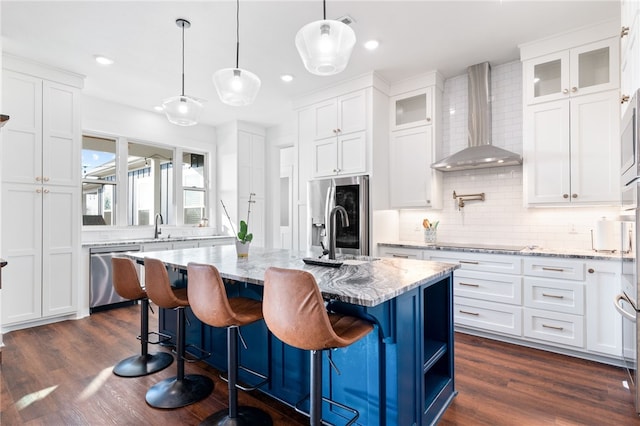 kitchen with white cabinetry, stainless steel appliances, wall chimney range hood, and a sink