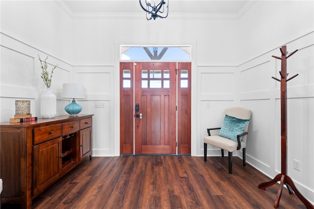 foyer entrance featuring dark wood-type flooring, crown molding, and an inviting chandelier