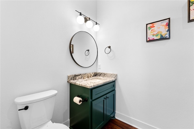 half bathroom featuring vanity, toilet, wood finished floors, and baseboards