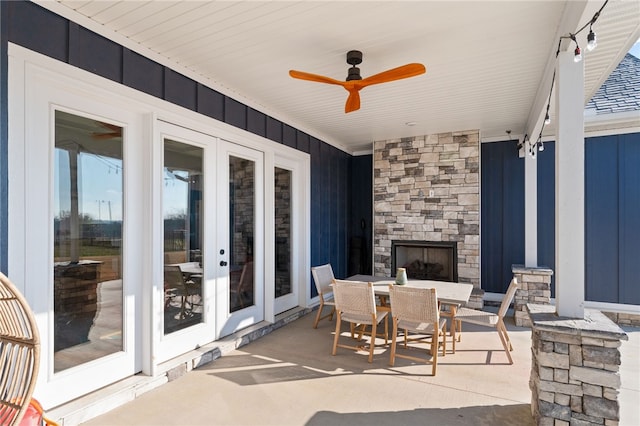 view of patio with outdoor dining space, an outdoor stone fireplace, and ceiling fan