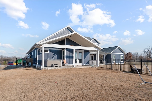 view of front facade featuring fence private yard, french doors, a hot tub, and board and batten siding