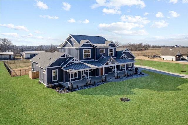 back of house with a standing seam roof, a porch, fence, a yard, and board and batten siding