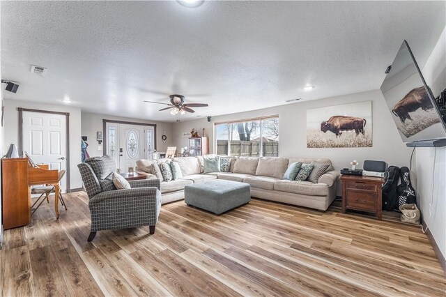 living room featuring a textured ceiling, light hardwood / wood-style floors, and ceiling fan