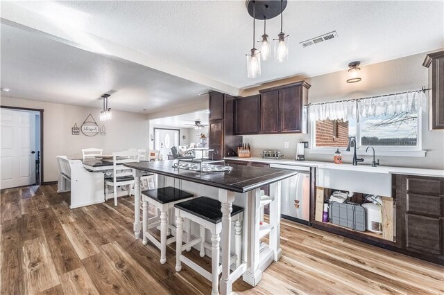 kitchen with dishwasher, a center island, ceiling fan, decorative light fixtures, and dark brown cabinetry