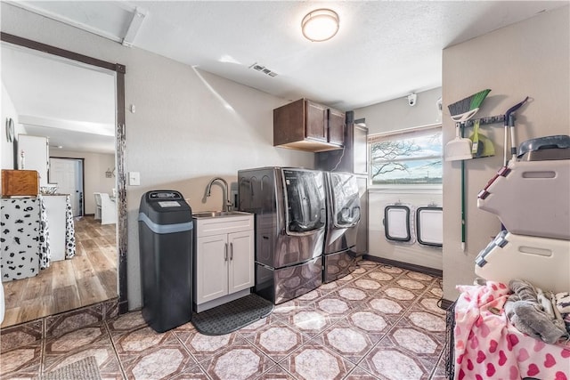 laundry area featuring cabinets, washing machine and dryer, sink, and a textured ceiling