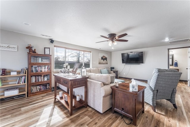 living room featuring a textured ceiling, ceiling fan, and light hardwood / wood-style flooring