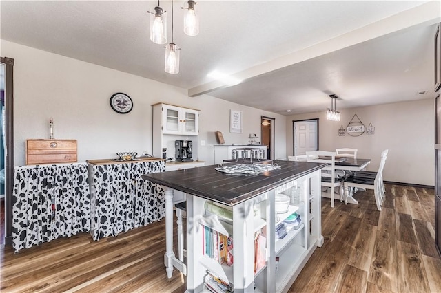 kitchen with hanging light fixtures, white cabinetry, and dark hardwood / wood-style floors