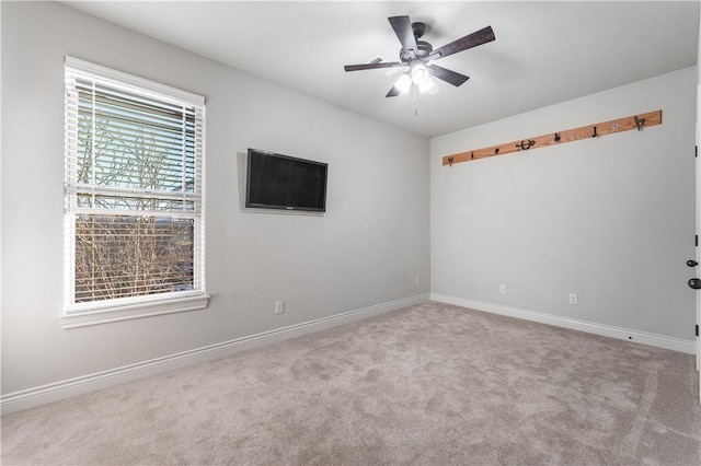 unfurnished room with baseboards, a ceiling fan, and light colored carpet