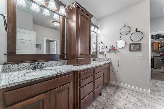 bathroom with double vanity, visible vents, a sink, baseboards, and tile patterned floors