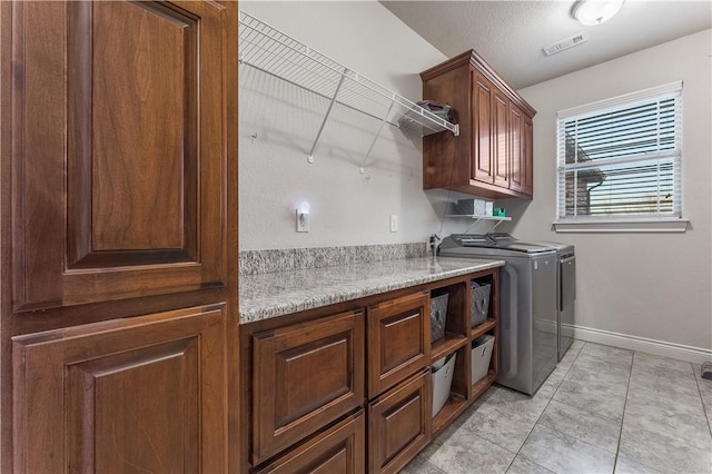 laundry area with cabinet space, light tile patterned floors, baseboards, visible vents, and washing machine and clothes dryer