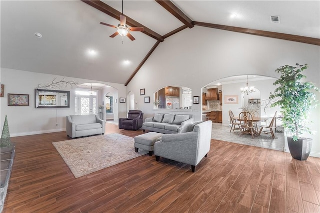 living area featuring arched walkways, ceiling fan with notable chandelier, visible vents, beamed ceiling, and dark wood finished floors