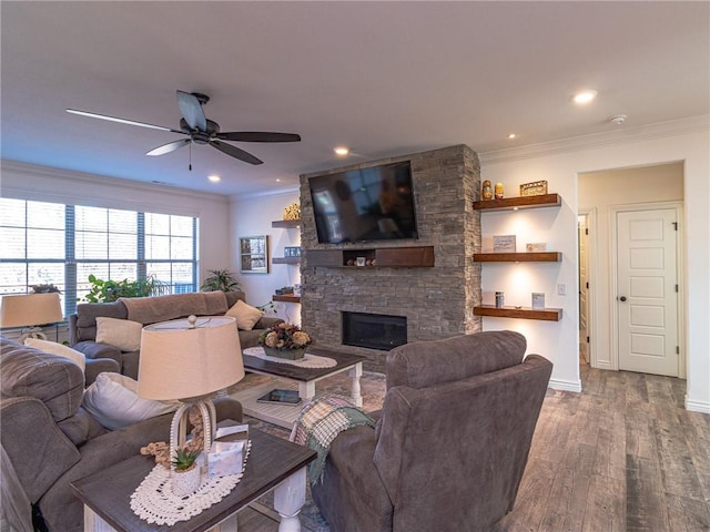 living room featuring a stone fireplace, ceiling fan, wood-type flooring, and ornamental molding