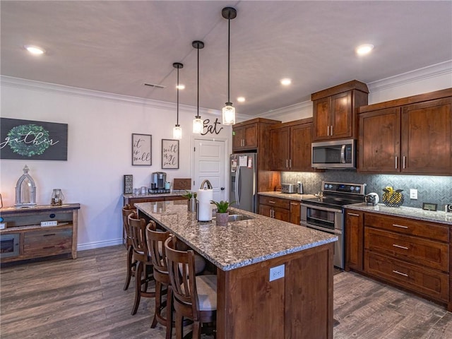 kitchen featuring stainless steel appliances, a center island with sink, and dark stone countertops