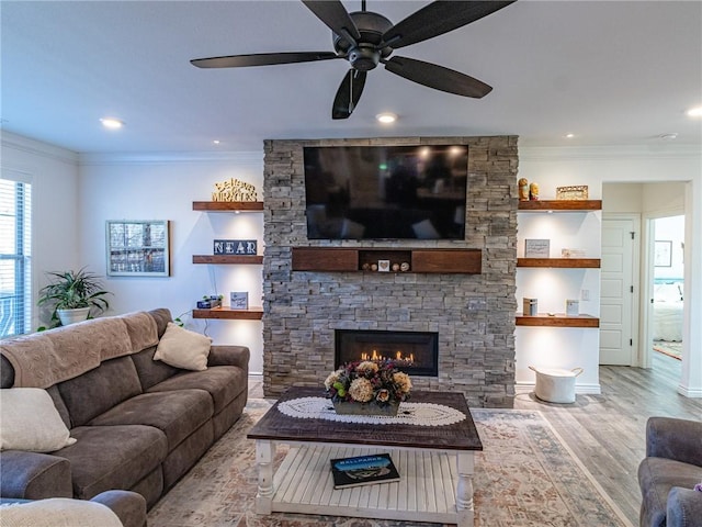 living room featuring a fireplace, light hardwood / wood-style floors, ceiling fan, and crown molding