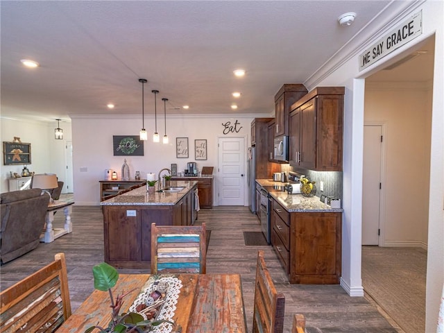 kitchen with light stone countertops, stainless steel appliances, sink, a center island with sink, and dark hardwood / wood-style floors