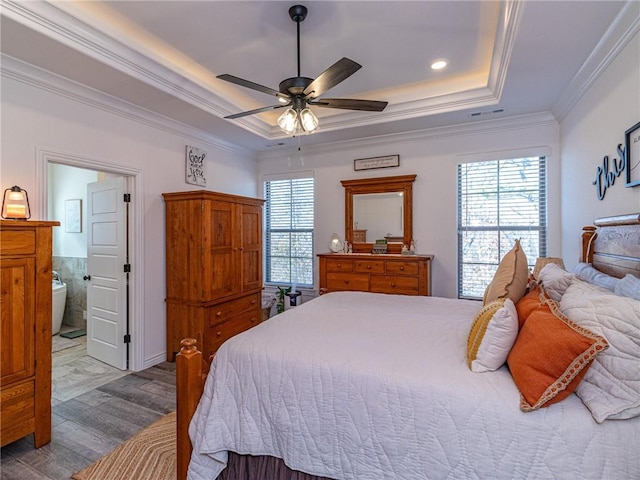 bedroom featuring connected bathroom, ceiling fan, crown molding, hardwood / wood-style floors, and a tray ceiling