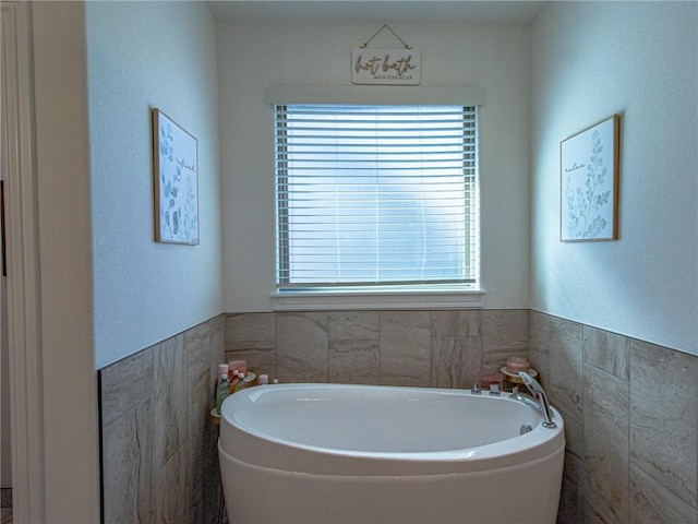 bathroom with a tub and tile walls