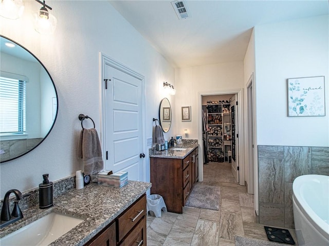 bathroom featuring vanity, tile walls, and a bathing tub