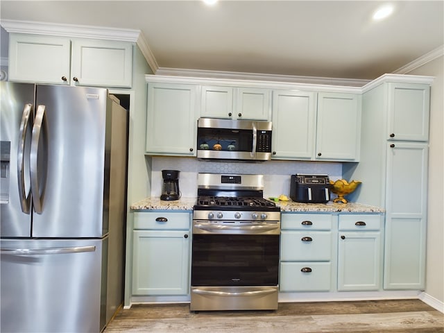 kitchen featuring light stone counters, light wood finished floors, appliances with stainless steel finishes, and ornamental molding