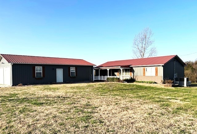 view of front of property with an outbuilding, metal roof, and a front lawn