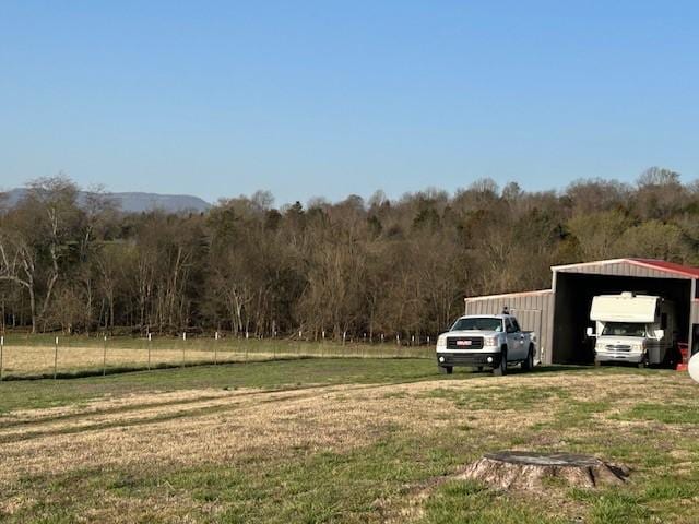 view of yard with a carport and a view of trees