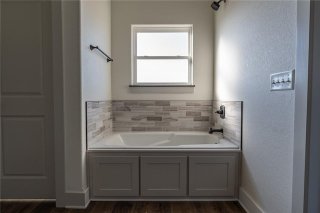 bathroom with wood-type flooring and a tub to relax in