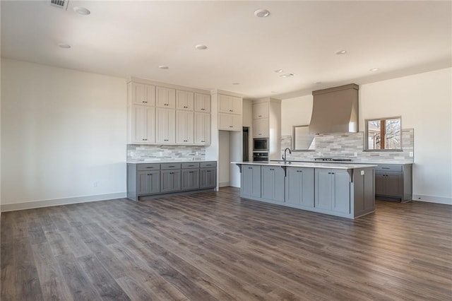 13121 Bethel Blacktop Rd, Farmington, AR 72730 - kitchen with gray cabinetry, a center island with sink, dark wood-style flooring, and wall chimney range hood