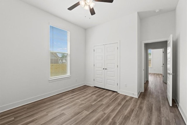 unfurnished bedroom with a ceiling fan, wood finished floors, baseboards, and a closet