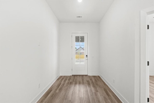 doorway to outside featuring visible vents, baseboards, and wood finished floors