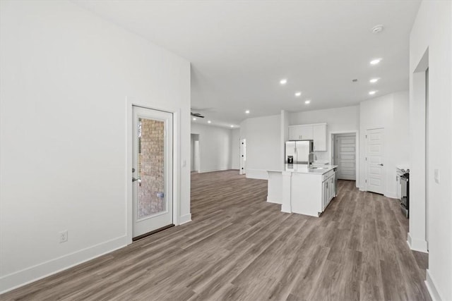 kitchen with stainless steel fridge with ice dispenser, open floor plan, an island with sink, wood finished floors, and a sink