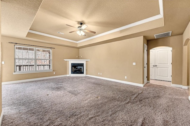 unfurnished living room with carpet flooring, ceiling fan, a textured ceiling, and a tray ceiling