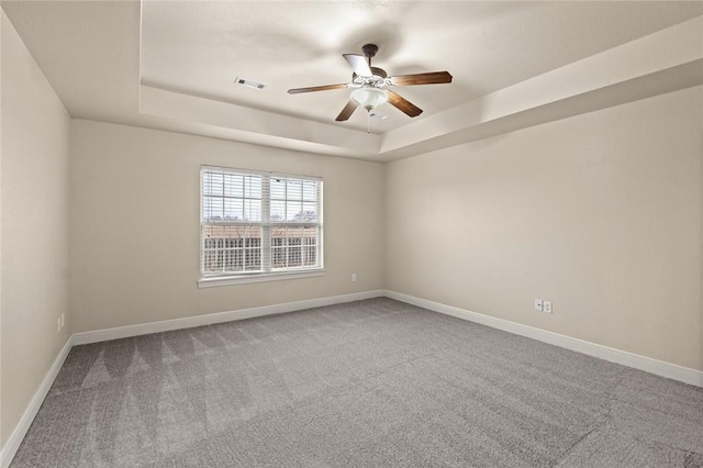 unfurnished room featuring a raised ceiling, ceiling fan, and carpet flooring