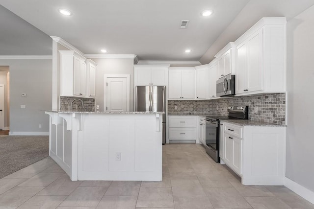 kitchen with stainless steel appliances, white cabinetry, light stone counters, and kitchen peninsula