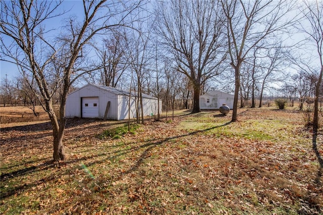 view of yard featuring a rural view, a garage, and an outbuilding