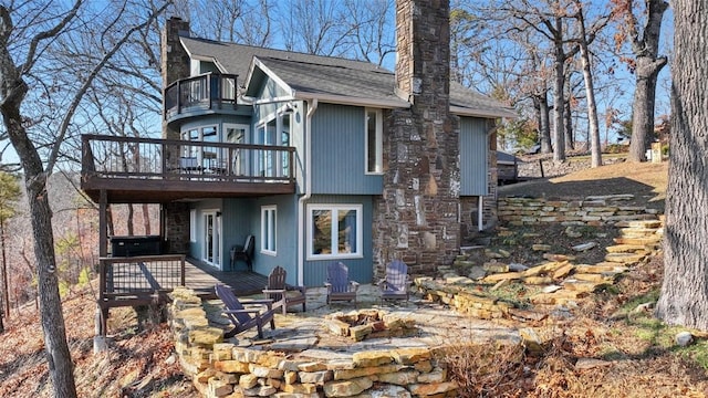 exterior space with a balcony, a deck, and an outdoor fire pit