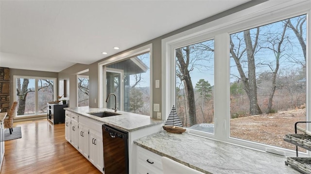 kitchen featuring light stone countertops, sink, black dishwasher, light hardwood / wood-style flooring, and white cabinets