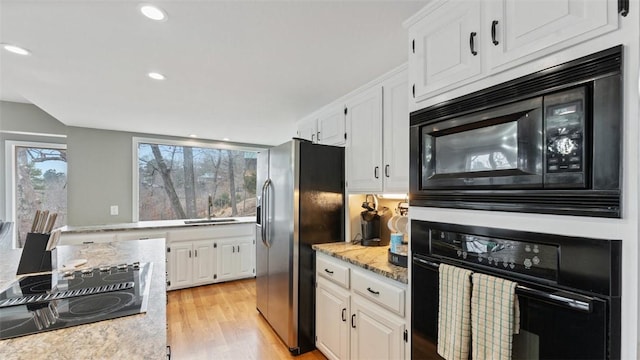 kitchen featuring white cabinetry, sink, black appliances, and light hardwood / wood-style floors