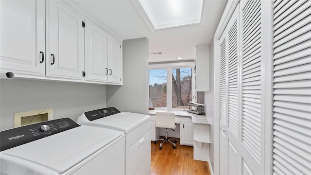 laundry area featuring cabinets, light hardwood / wood-style floors, and separate washer and dryer