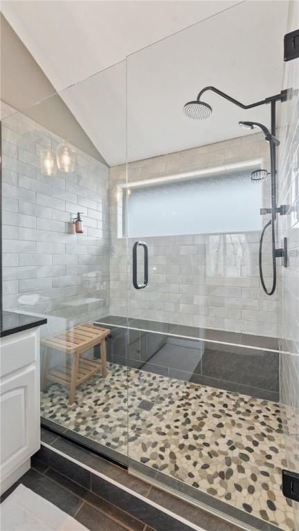 bathroom with a shower with door, vanity, and lofted ceiling