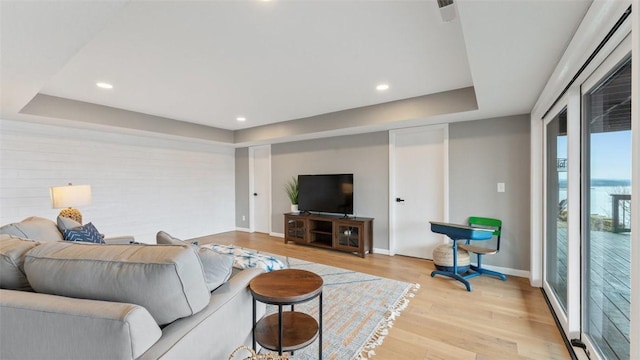 living room featuring a tray ceiling and light hardwood / wood-style floors