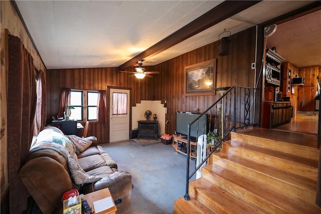 living room with ceiling fan, vaulted ceiling, and a wood stove