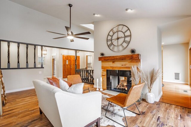 living room featuring a multi sided fireplace, light wood-type flooring, ceiling fan, and lofted ceiling